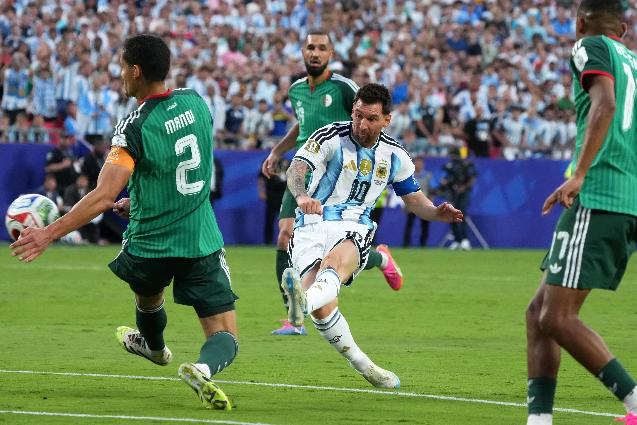 Lionel Messi scores his team’s first goal, framed by two Algeria defenders.