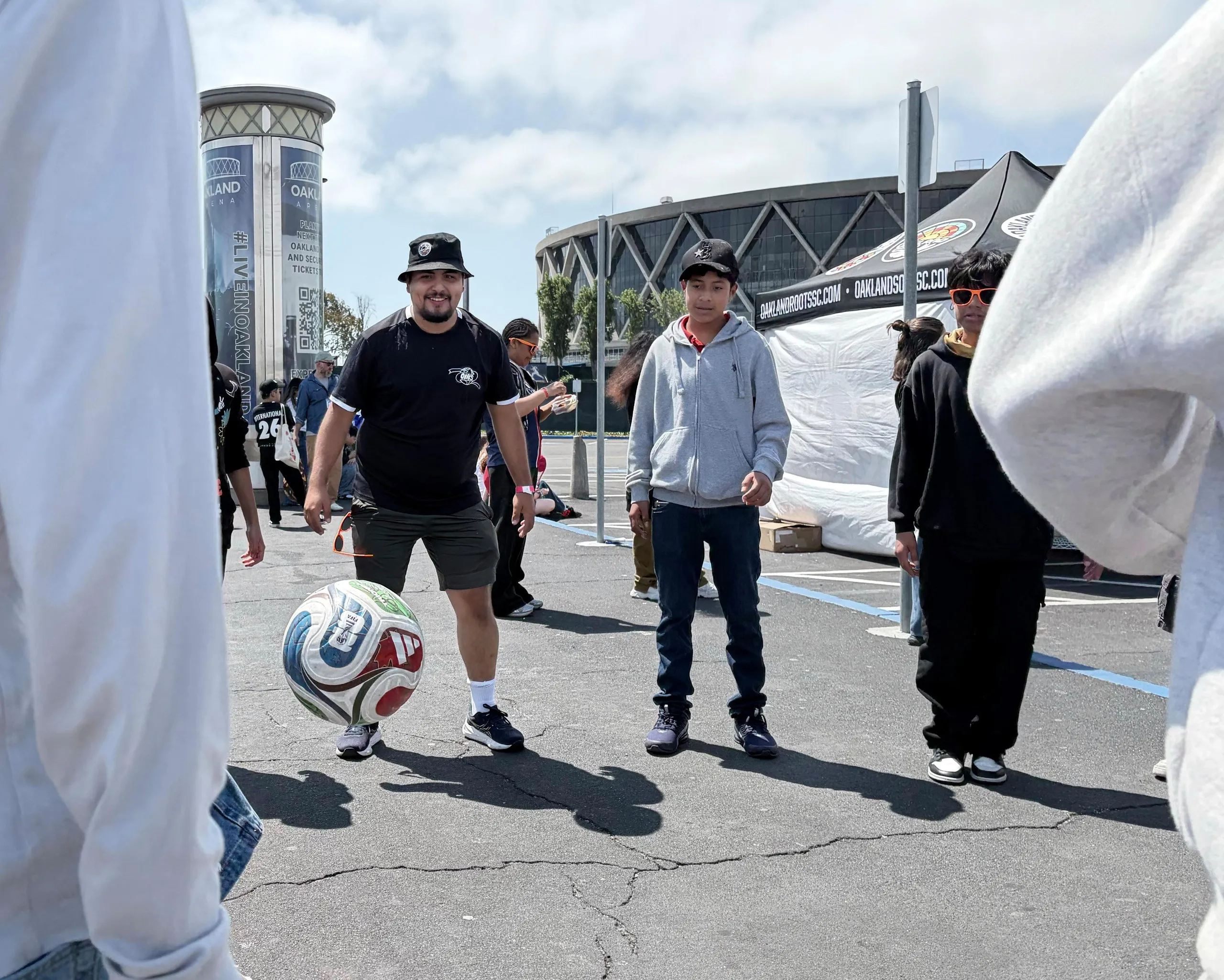 Bernardo Ramallo (left) playing soccer with students outside Oakland Coliseum