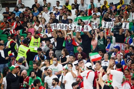 Security officers ask fans to take down a sign with the name Mahsa Amini during the 2022 World Cup Group B match between Iran and the USA