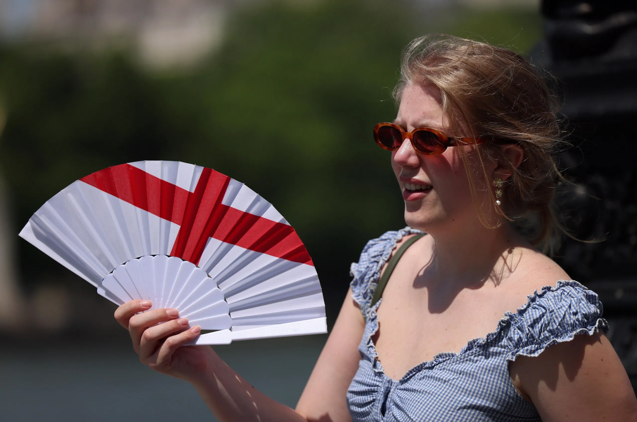 A woman uses a fan to cool down during a hot day in London