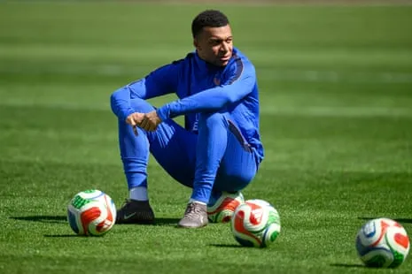 Kylian Mbappé sitting on a football Kylian Mbappé sitting on a football