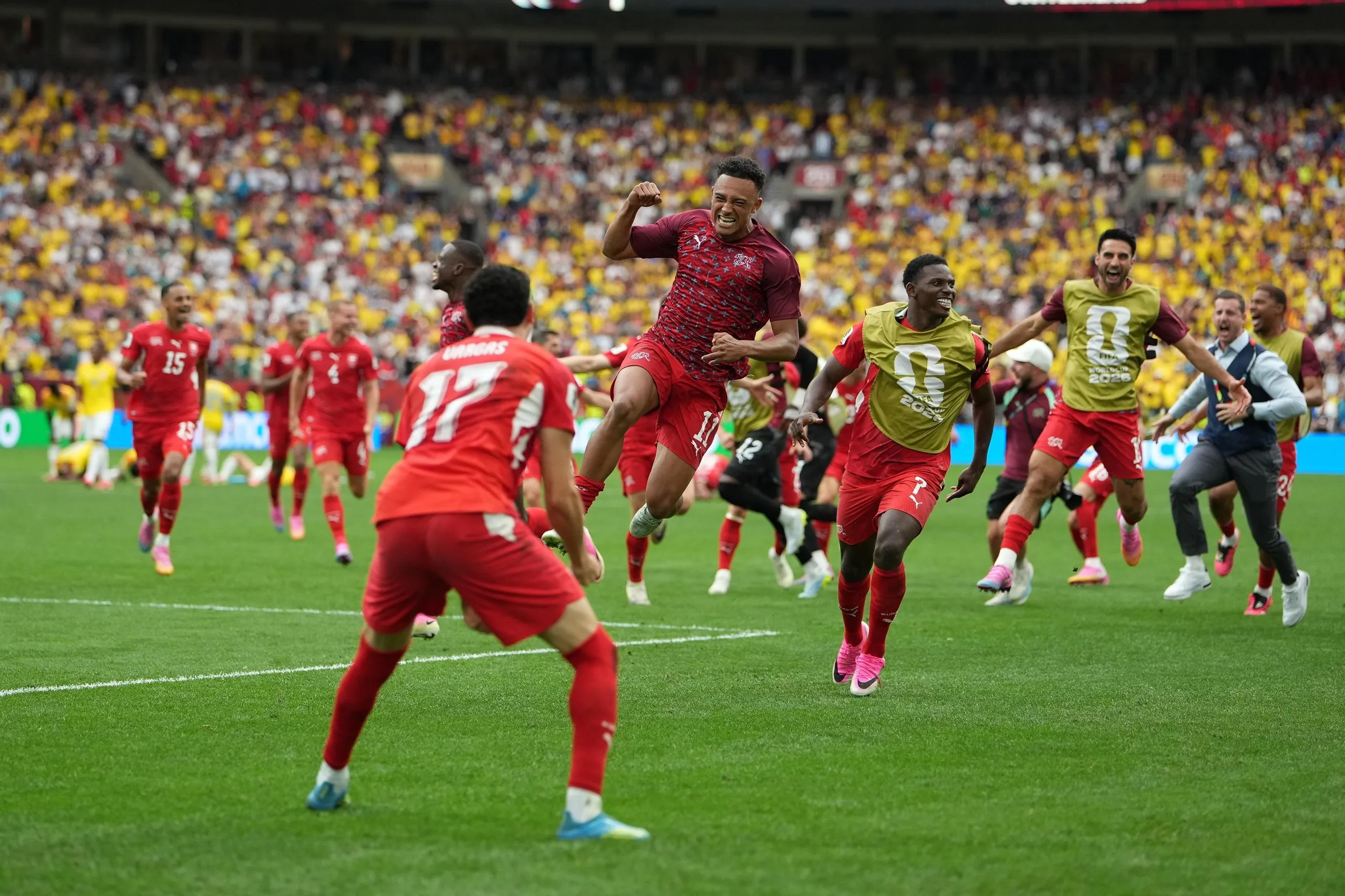 Switzerland players race to Ruben Vargas after his winning penalty.