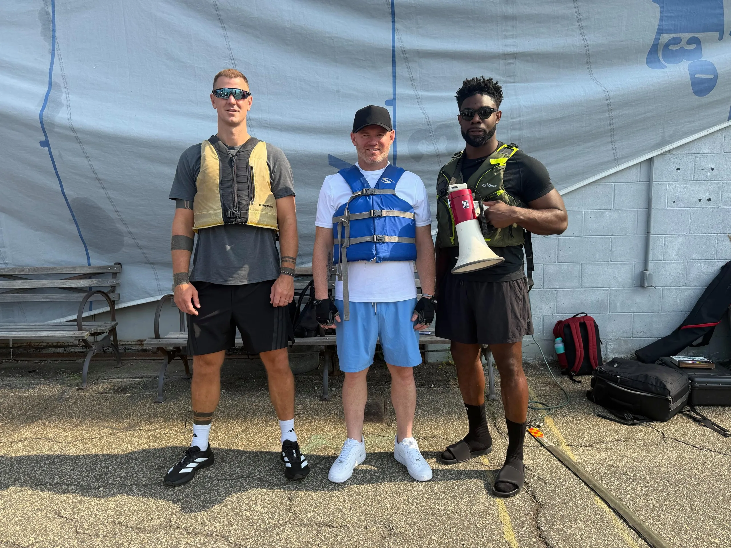 Joe Hart, Wayne Rooney, and Micah Richards ahead of them rowing on the Hudson in New York.